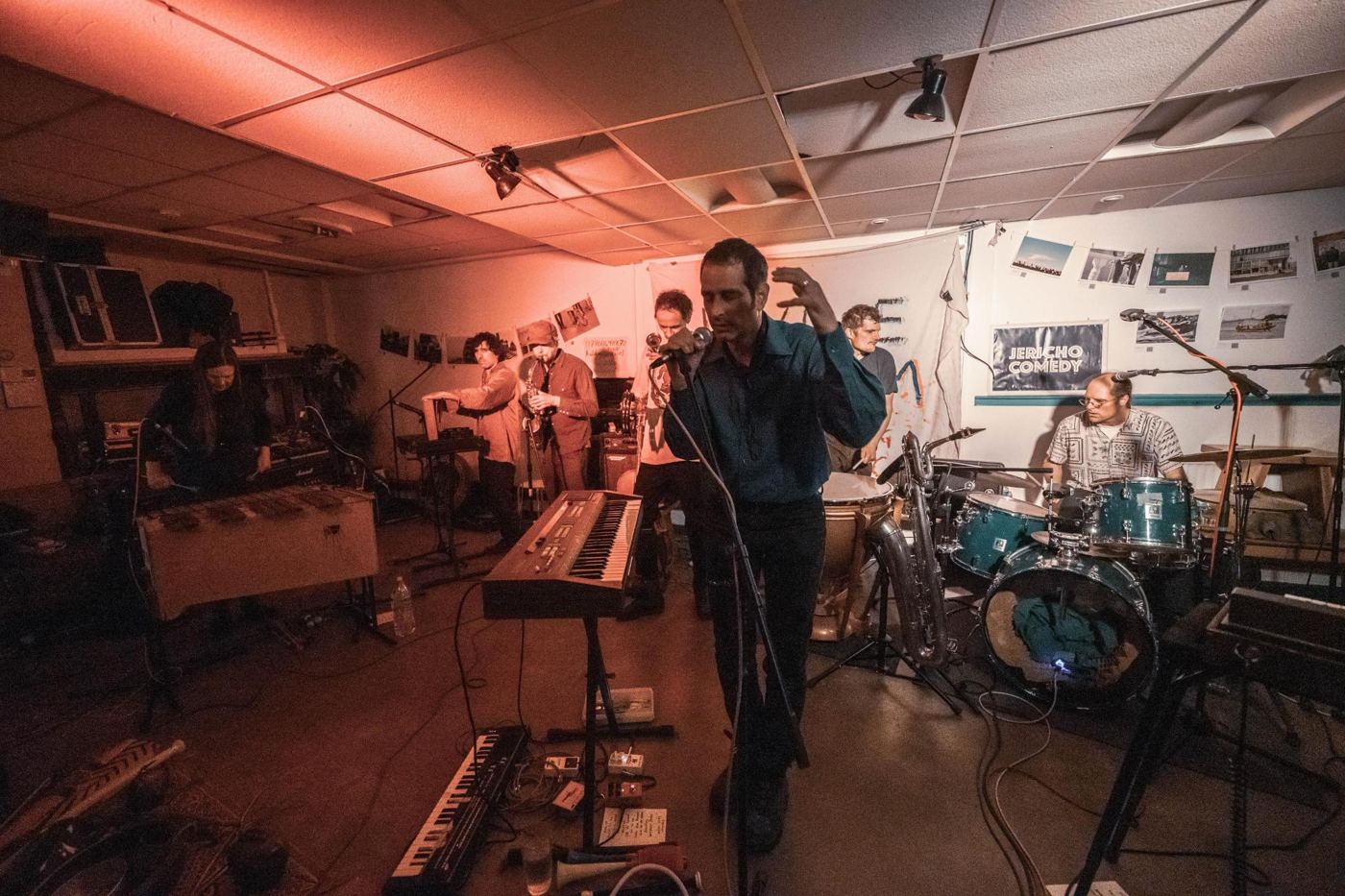 Kulku live in rotem Licht, Sänger am Mikrofon, dahinter Marimba, Saxophon und Schlagzeug